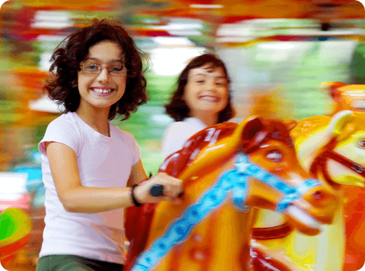 Two girls riding a carousel.