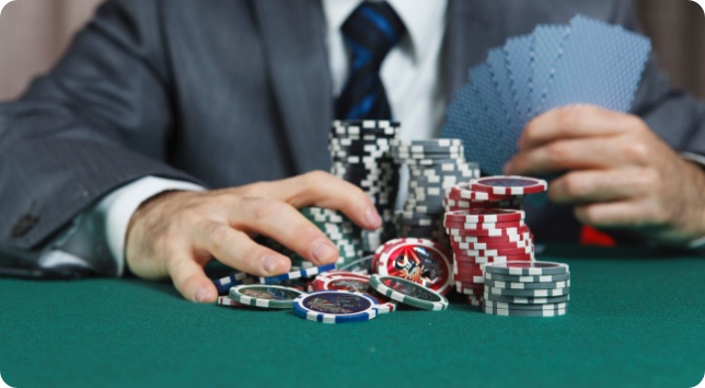 A man in a suit playing poker with chips and cards.