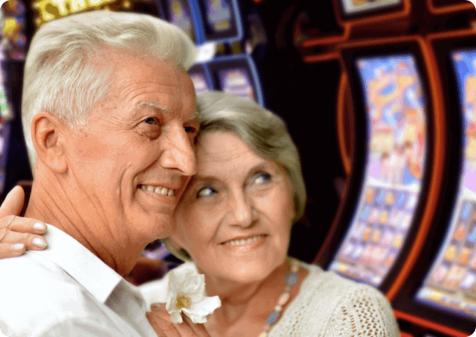 An older couple embracing in front of slot machines.