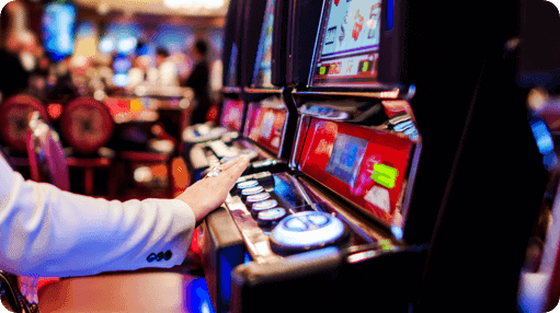 A man is playing a slot machine in a casino.