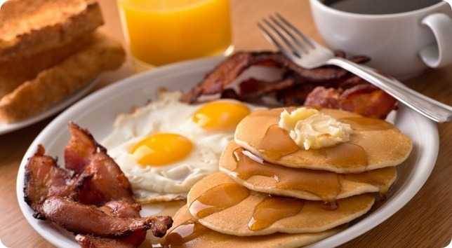 Pancakes, bacon, eggs and toast on a plate.