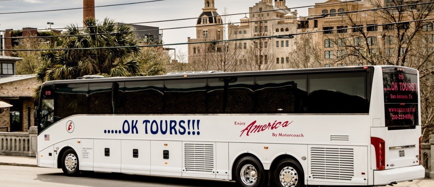 A white bus is parked in front of a building.