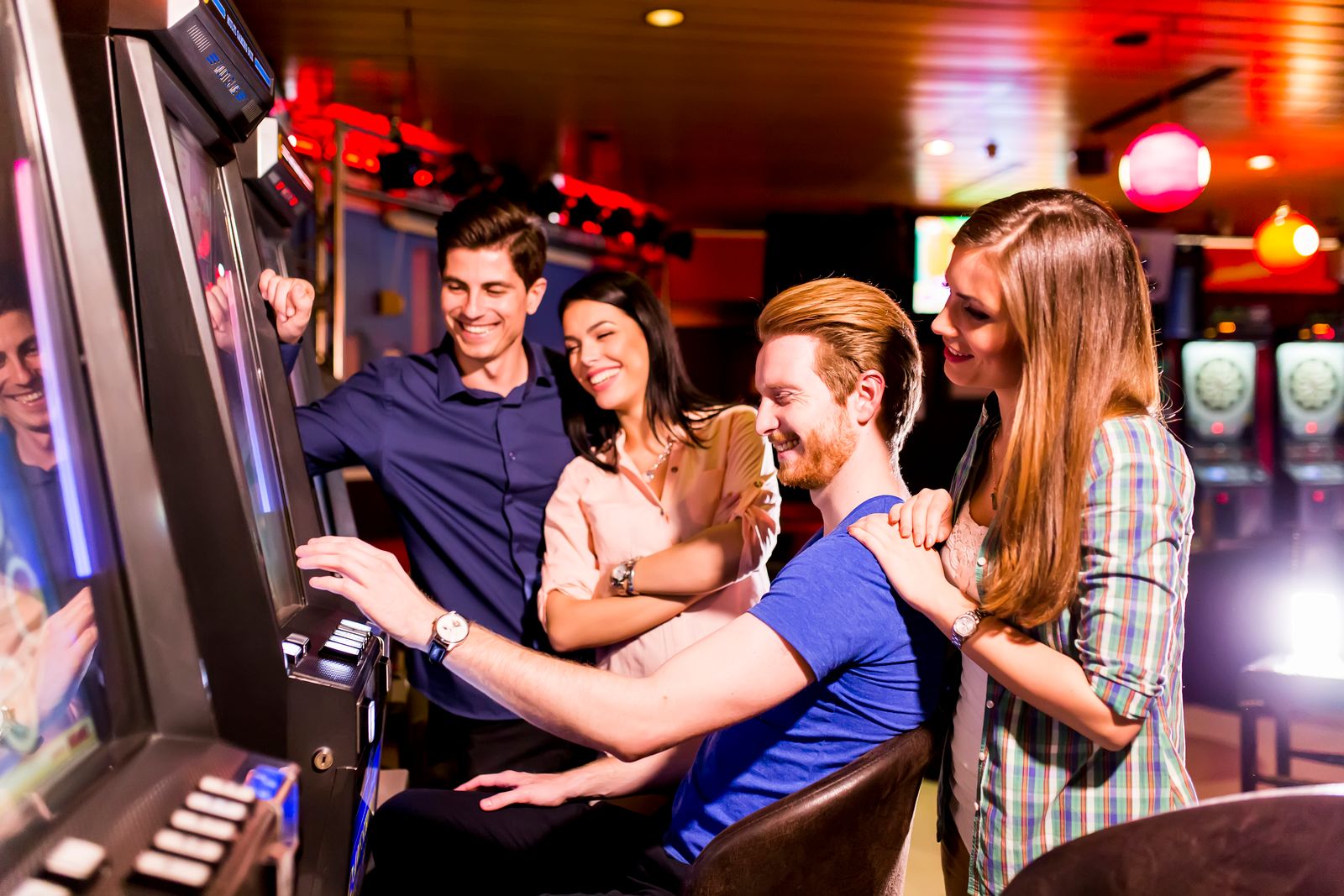 A group of people playing slot machines in a casino.