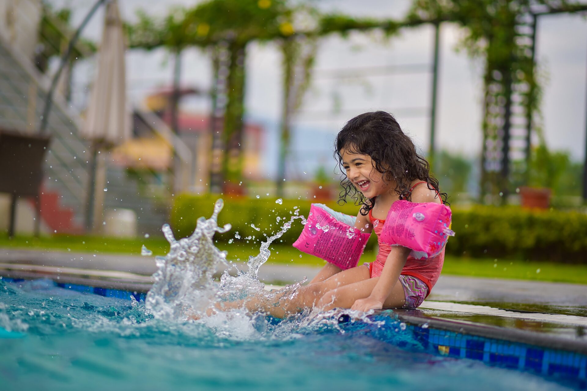 A little girl splashing around in a swimming pool.