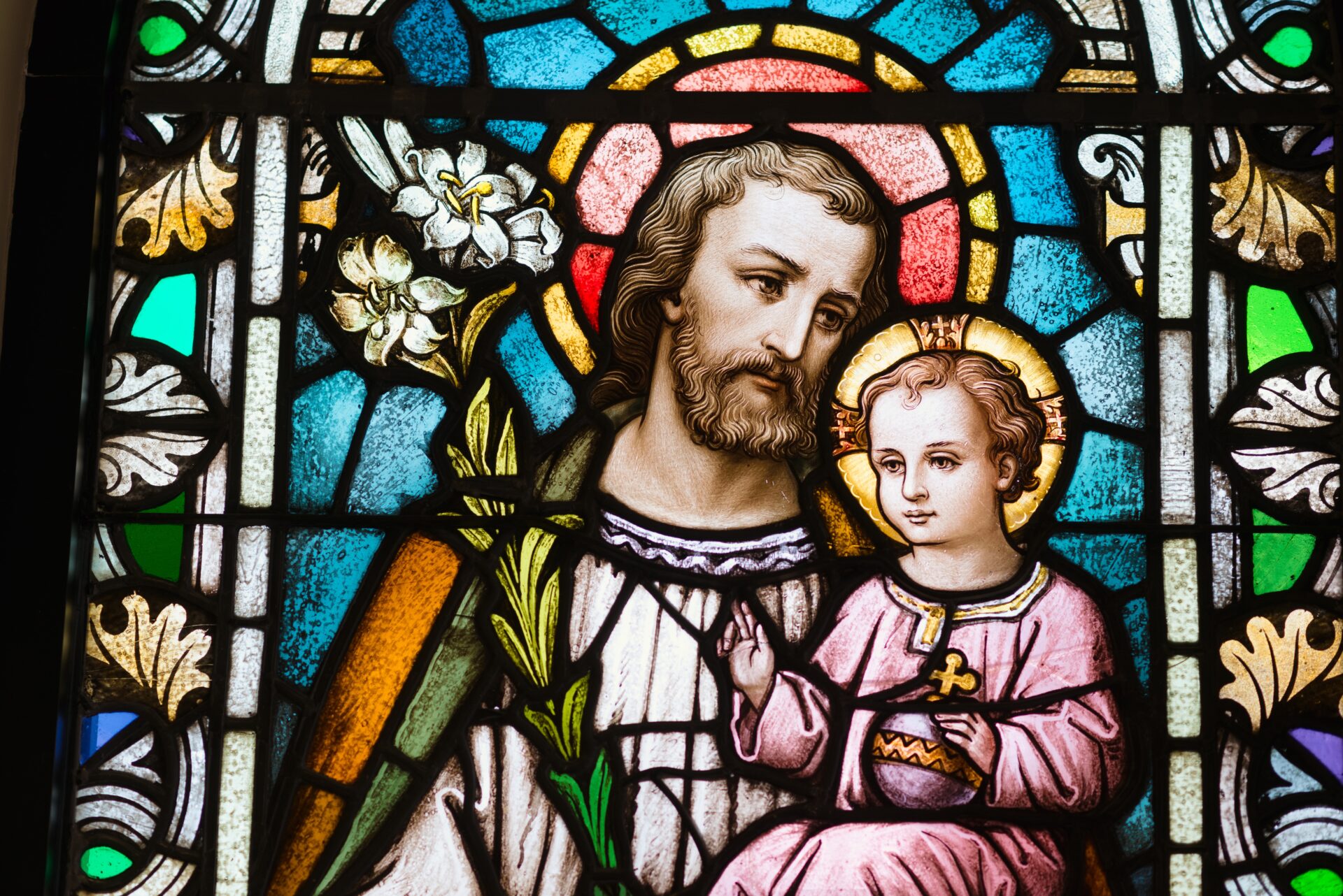 A stained glass window showing jesus holding a child.