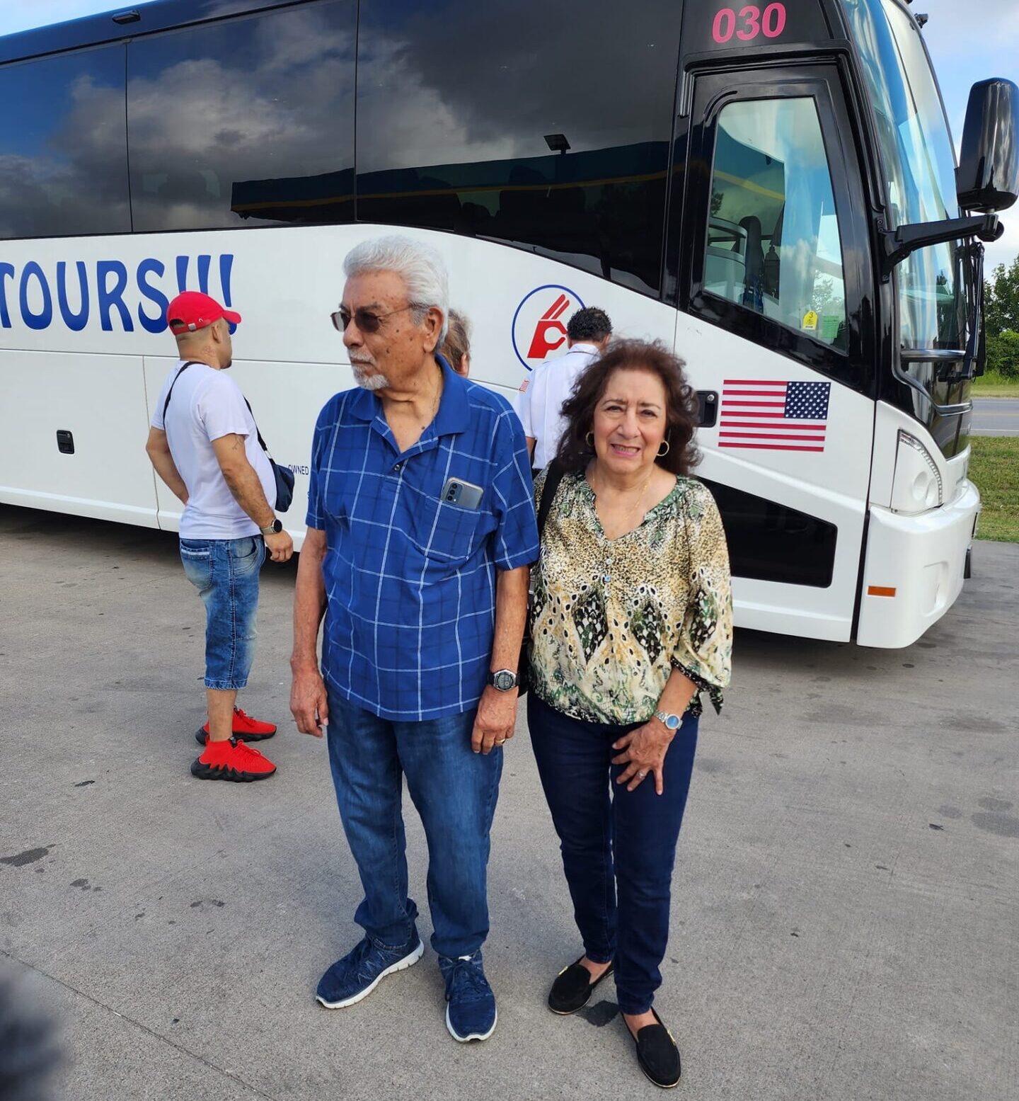 A man and woman standing in front of a tour bus.