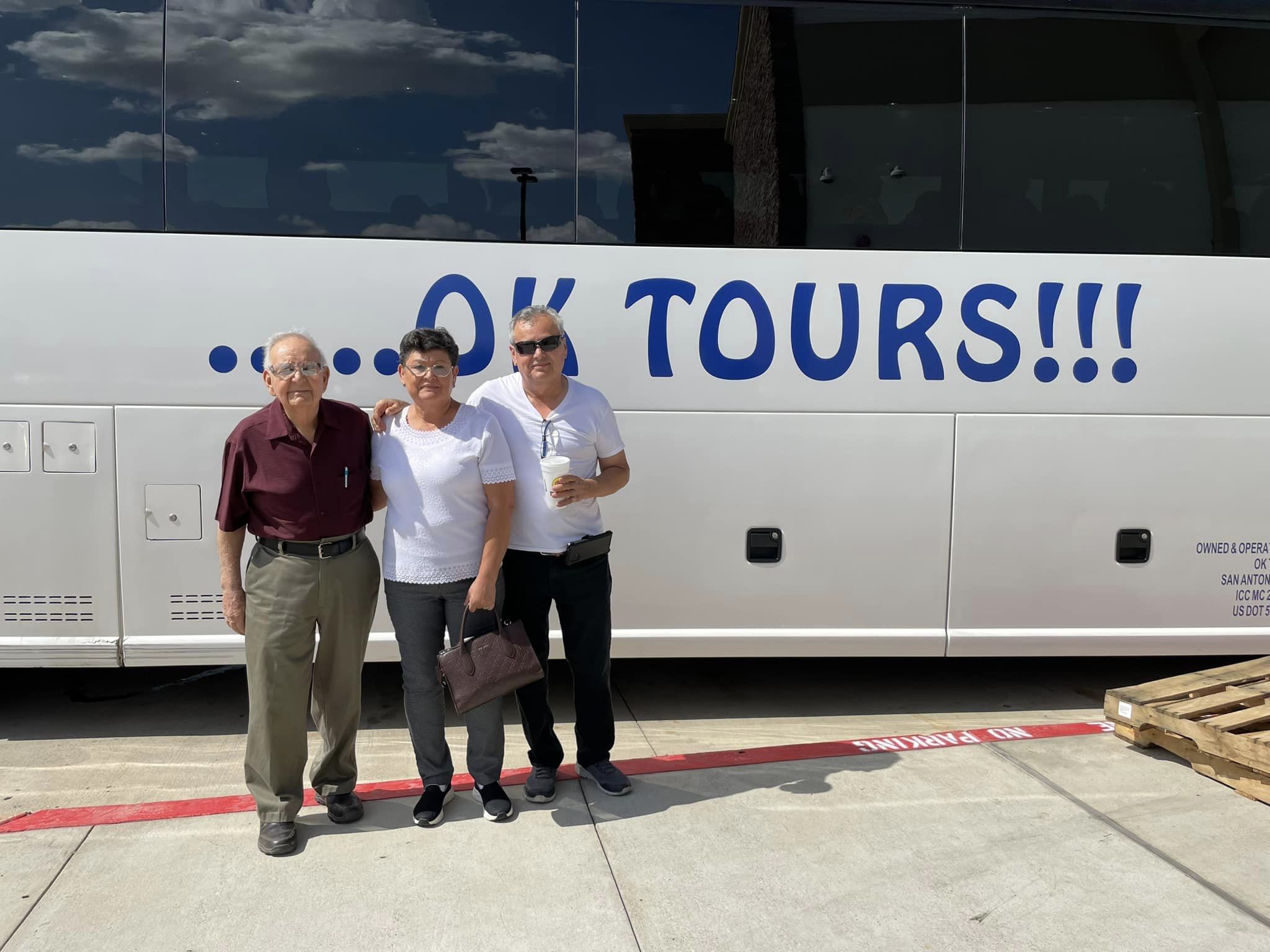 Three people standing in front of a bus.
