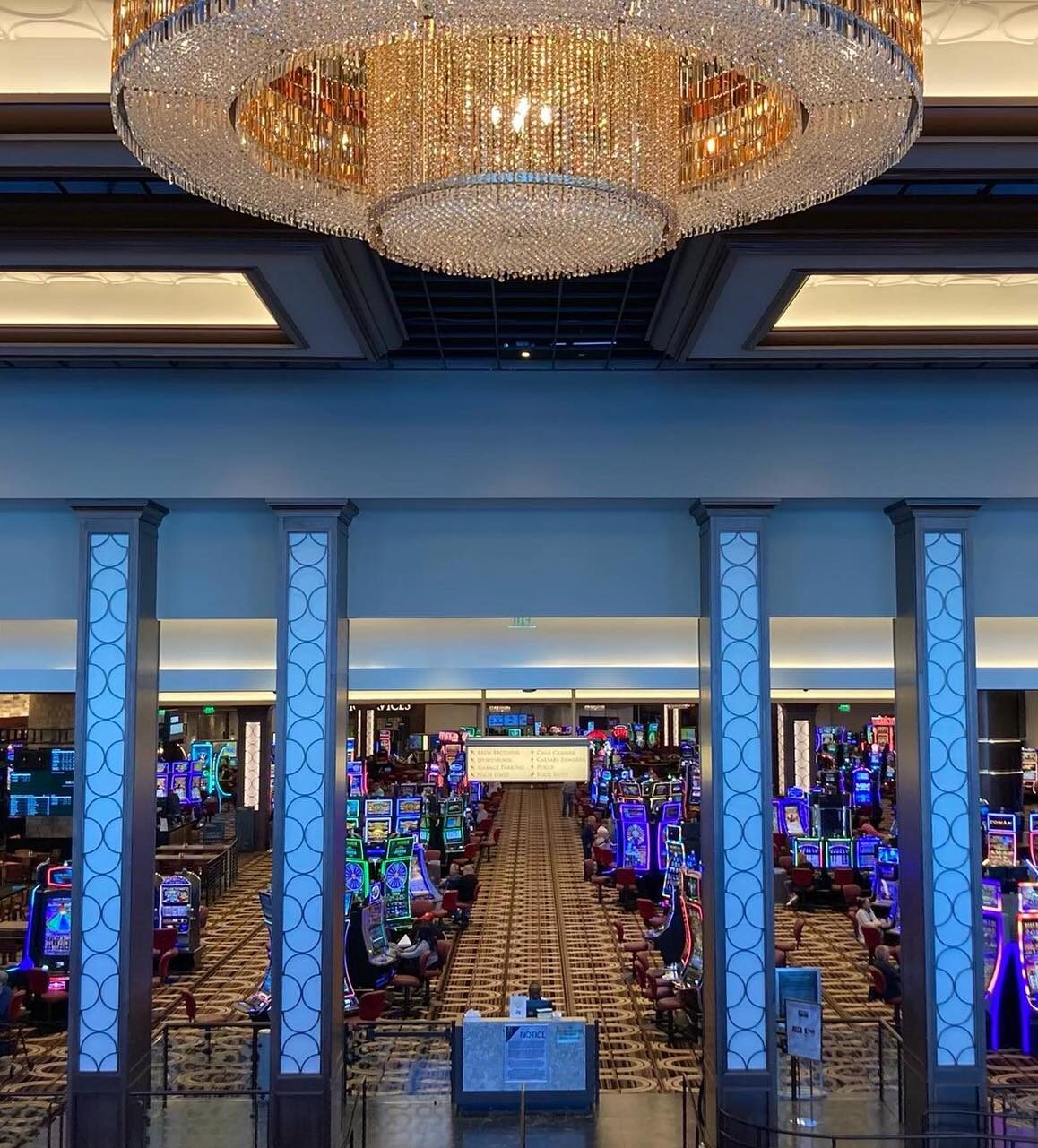 The inside of a casino with slot machines and a chandelier.