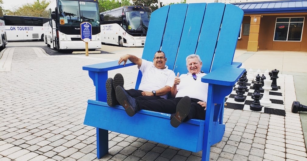 Two men sitting in a blue adirondack chair.