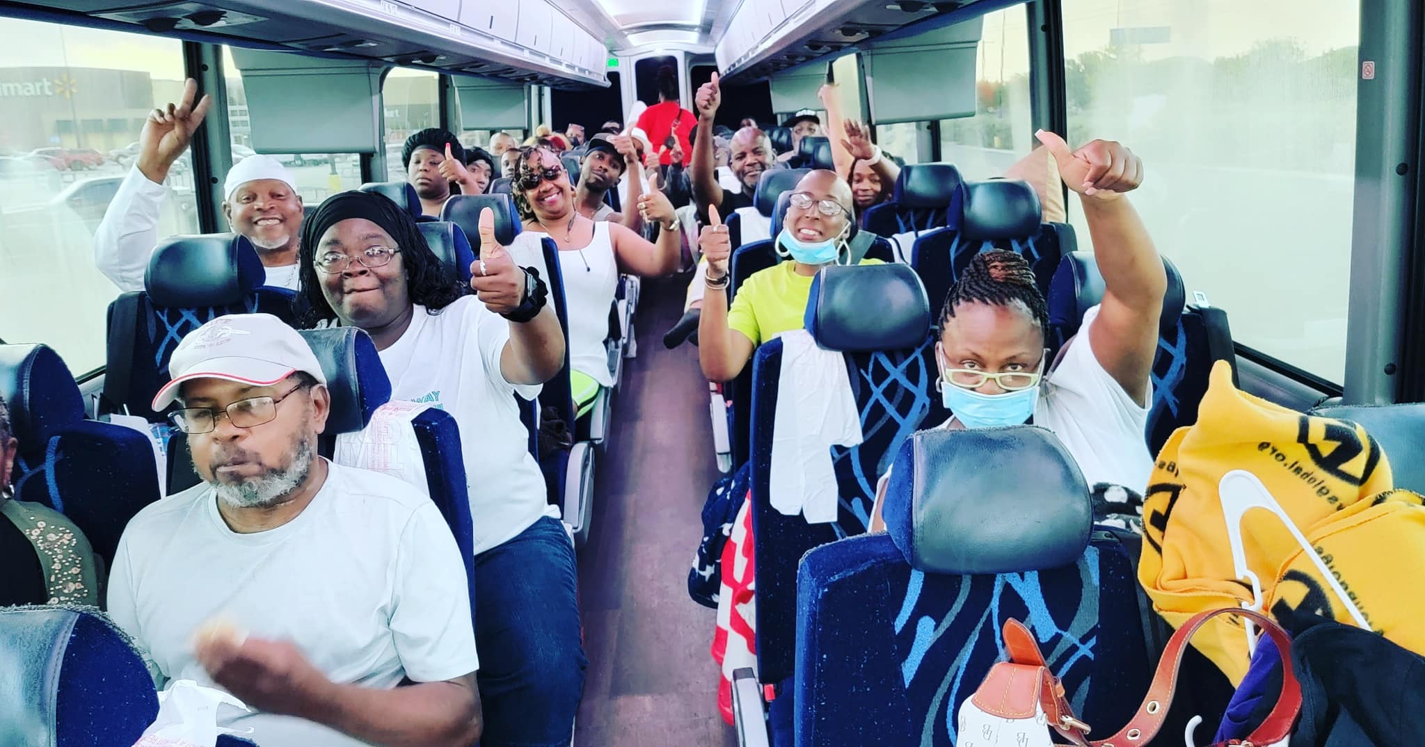 A group of people on a bus waving their hands.
