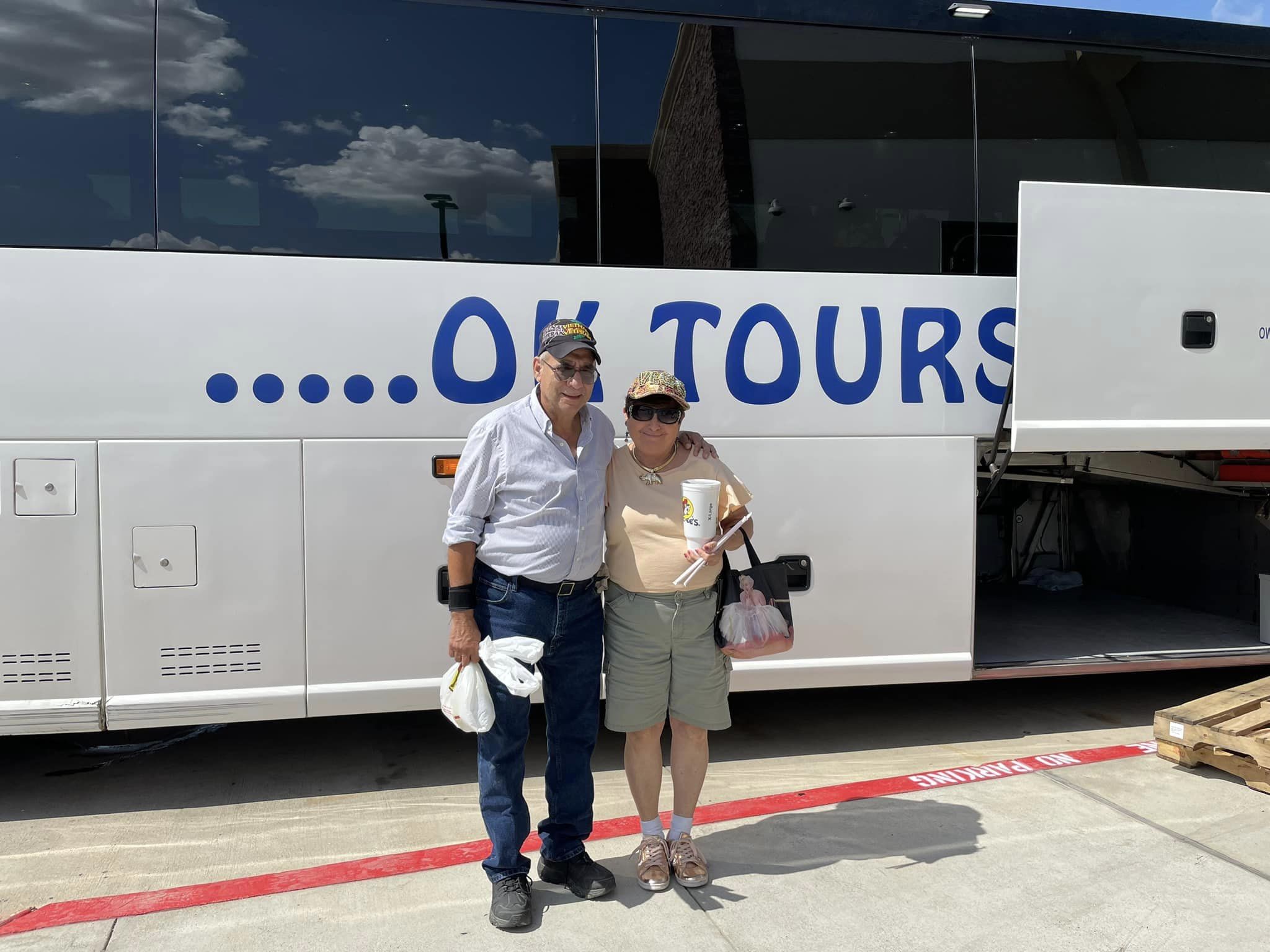 A man and woman standing in front of a large bus.