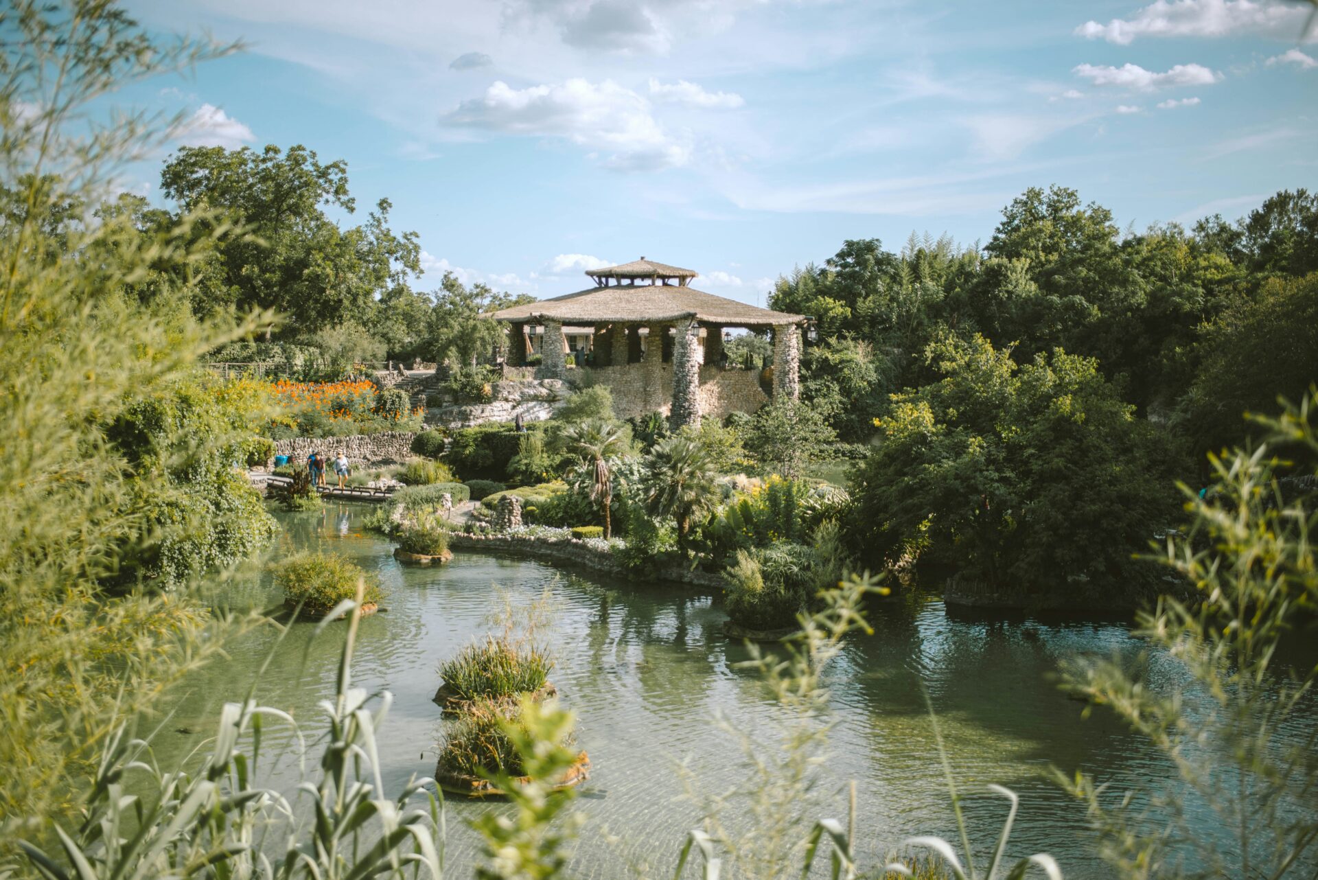 A gazebo sits in the middle of a pond.